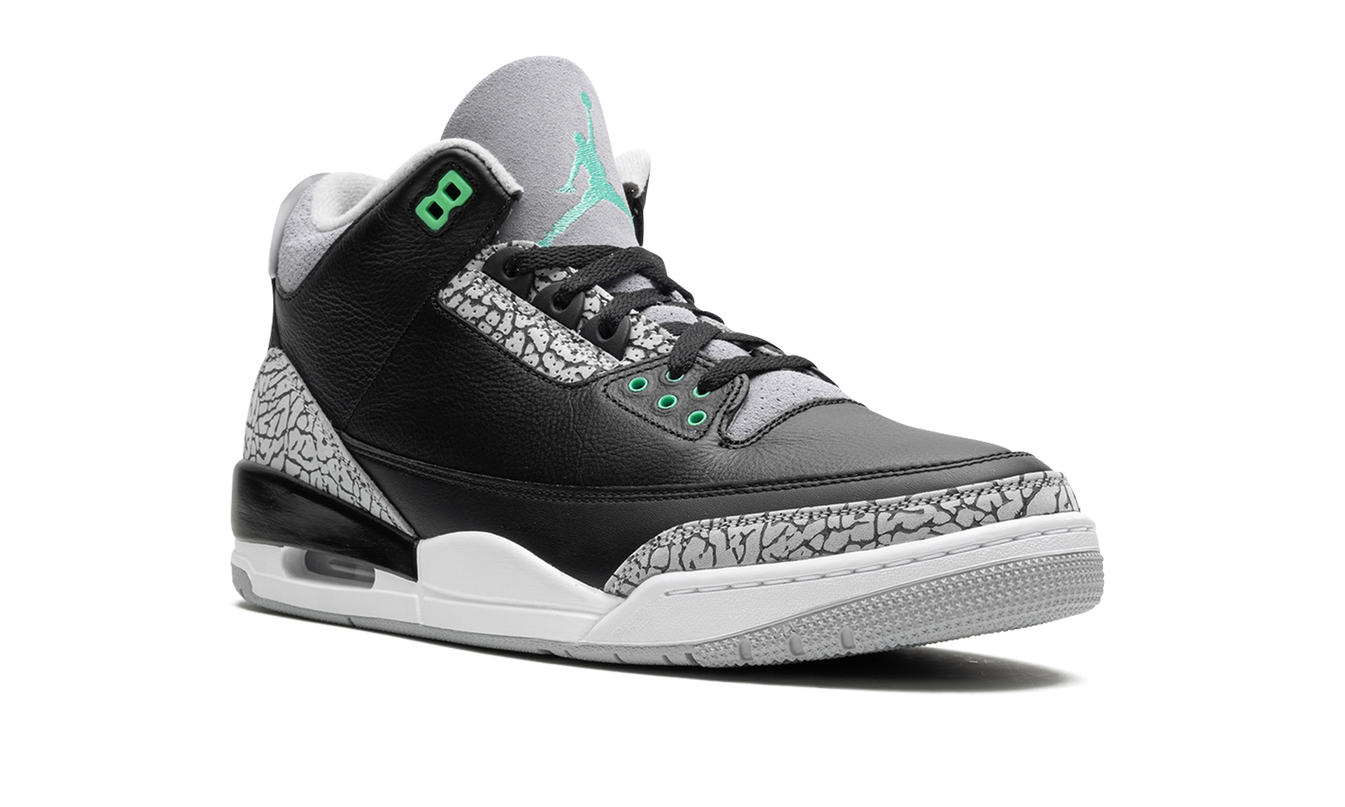Groene glow Air Jordan 3 Retro schoenen met leren bovenwerk en witte details, gelegen op een lichtbruine vloer.