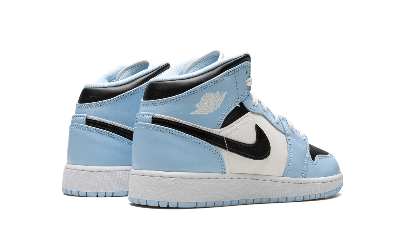 Lichte blauwe Air Jordan 1 Mid GS schoenen met witte details en zwart logo, zichtbaar van de zijkant.