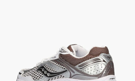 Witte en bruine Saucony ProGrid Omni 9 OG sneakers met witte zool en sportieve stijl, gedragen door een model.
