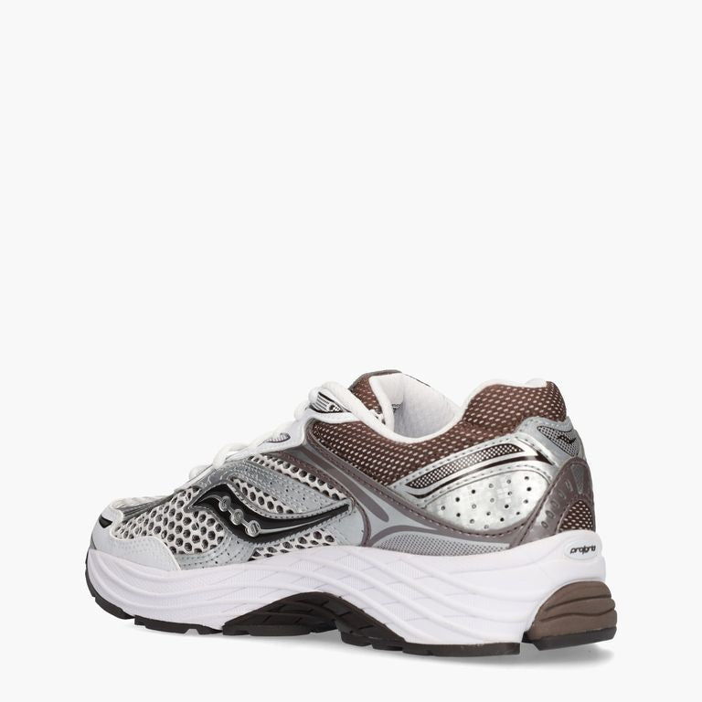 Witte en bruine Saucony ProGrid Omni 9 OG sneakers met witte zool en sportieve stijl, gedragen door een model.