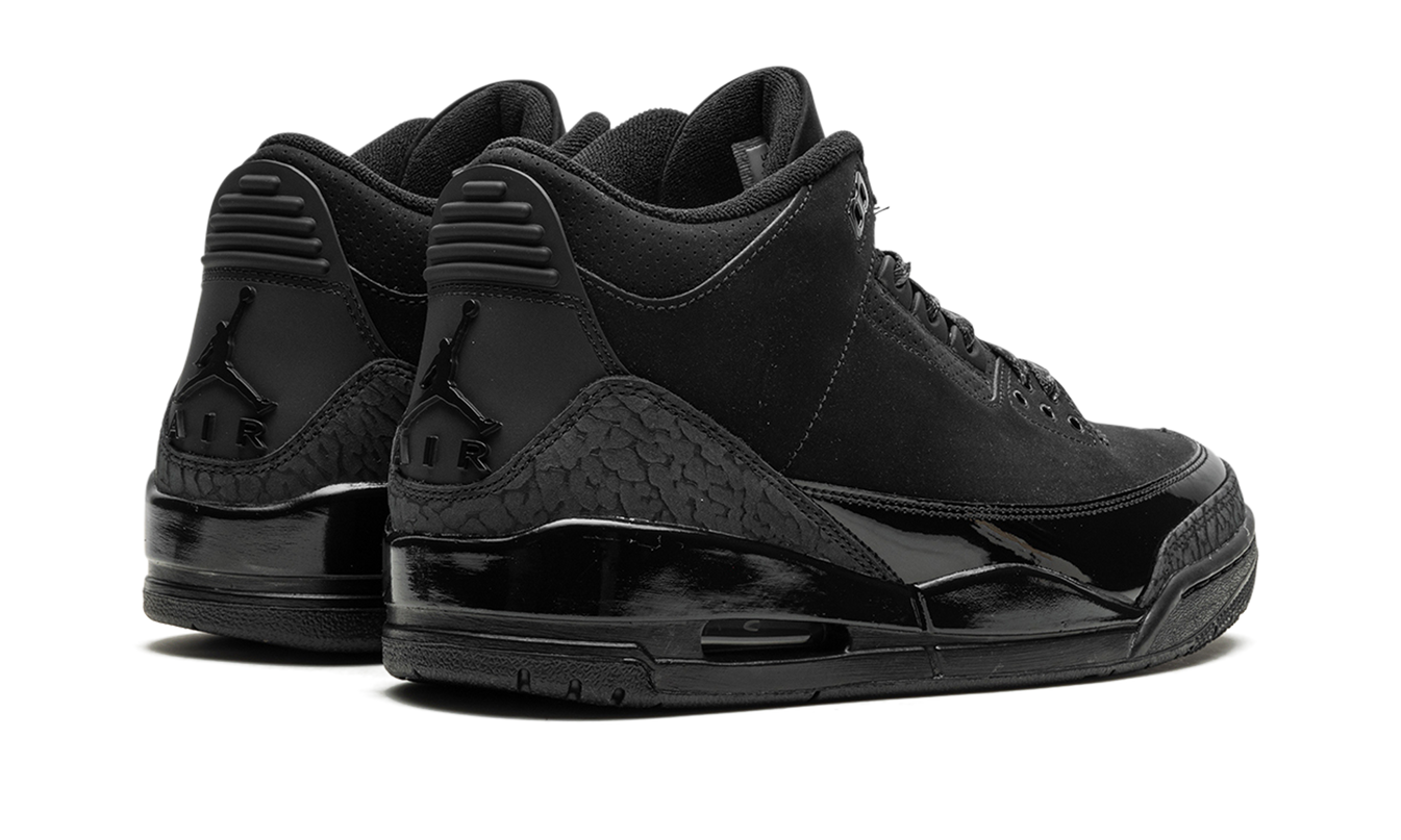 Zwarte Air Jordan 3 "Black Cat 2025" schoenen met leren bovenkant en witte zool, gedragen door een model.