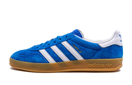 Blauwe Adidas Gazelle Indoor schoenen met witte details en zwarte zool, geschikt voor binnen sporten.