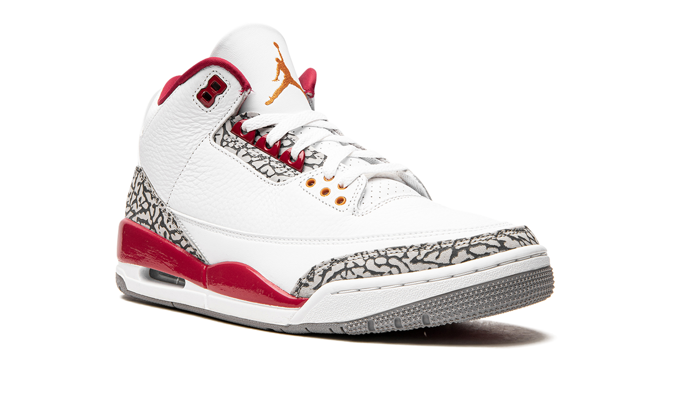 Lichte Air Jordan 3 "Cardinal" sneakers met rood leer en witte details, zichtbaar op een neutrale achtergrond.