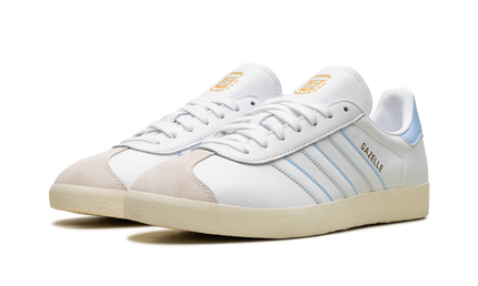 Lage Adidas Gazelle schoenen in wit en rood met Argentinië-merklogo, zichtbaar op de schoenen, voor dames of heren.
