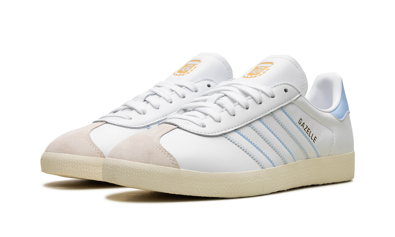 Lage Adidas Gazelle schoenen in wit en rood met Argentinië-merklogo, zichtbaar op de schoenen, voor dames of heren.