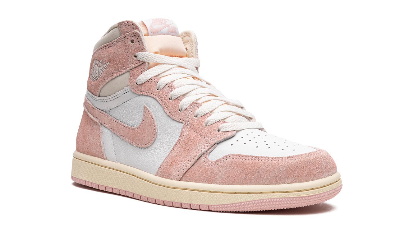 Roze Air Jordan 1 WMNS sneakers met gewassen effect en witte details, gedragen door een model op een witte achtergrond.