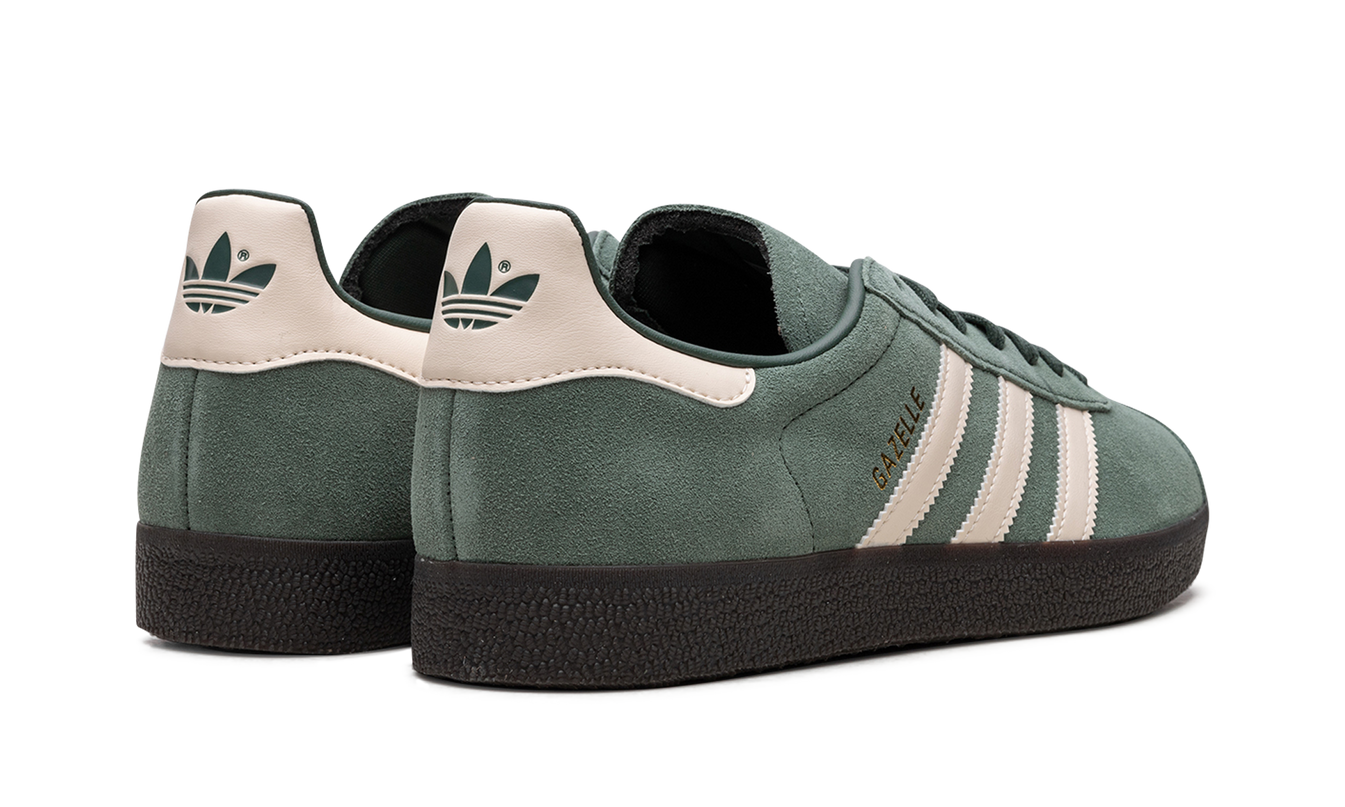 Donkerblauwe Adidas Gazelle "Mexico" schoenen met witte details en leren bovenkant, gelegen op een witte achtergrond.