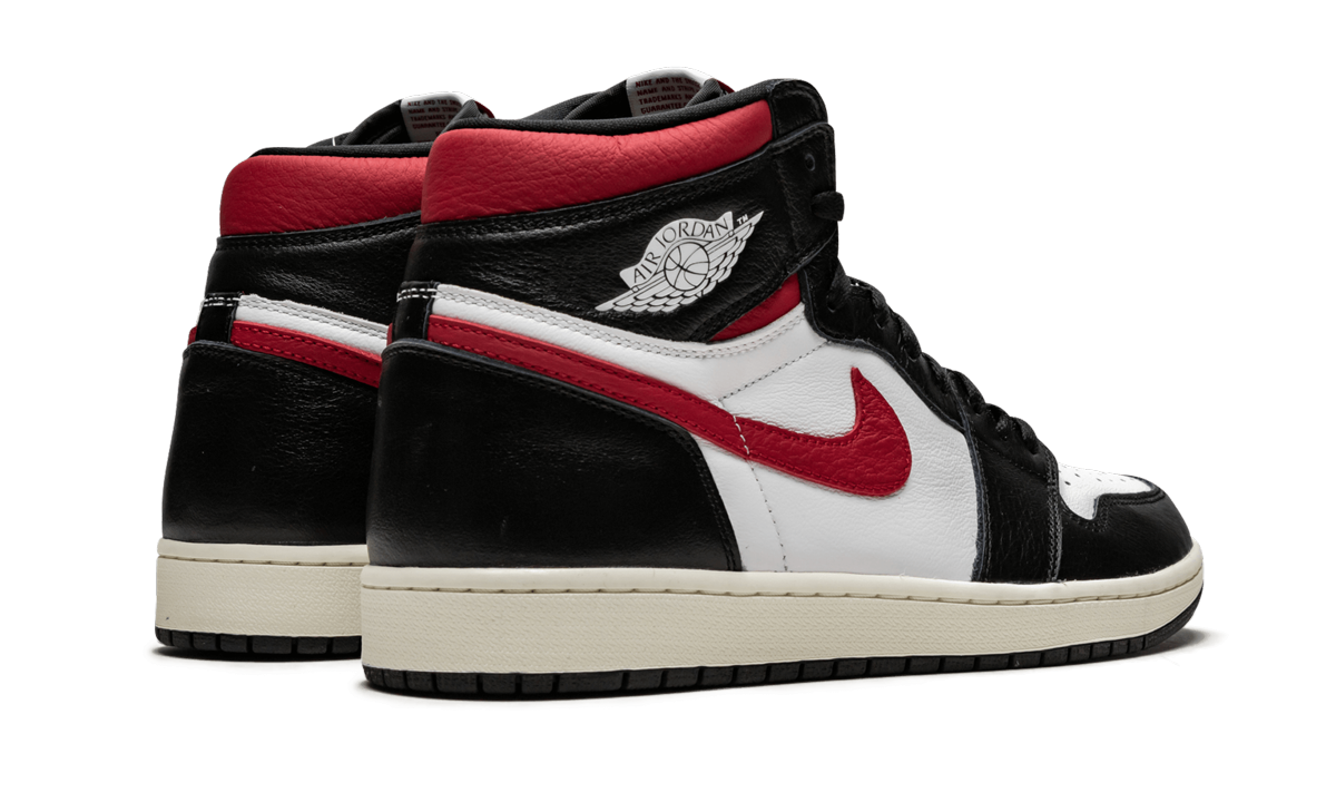 Witte en rode Air Jordan 1 Retro High OG sneakers met zwarte accenten, zichtbaar in de afbeelding.