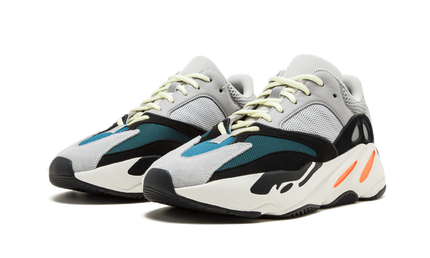 Witte en grijze Yeezy Boost 700 "Waverunner" sneakers met dikke zool en sportieve uitstraling, gedragen door een model.