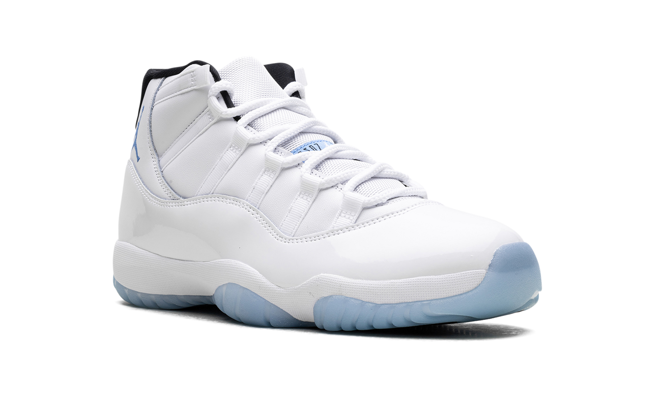 Witte en blauwe Air Jordan 11 Retro sneakers met glanzende afwerking en zwarte details, gedragen door een model.