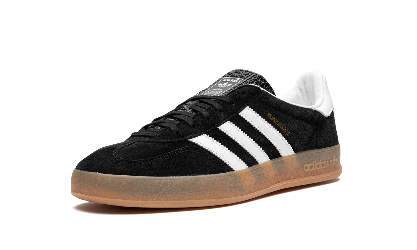 Zwarte Adidas Gazelle Indoor schoenen met witte en gumkleurige details, gedragen door een model, close-up van de schoen.