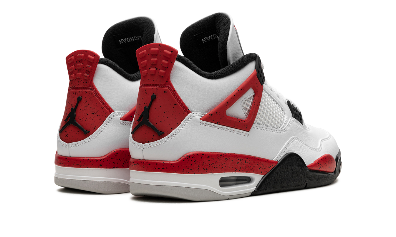 Zwarte en rode Air Jordan 4 sneakers met cementpatroon en witte zool, opvallend design, gedragen door een model.