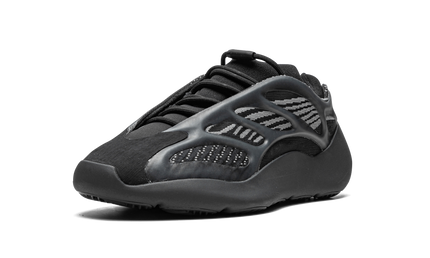 Donkere Yeezy 700 V3 sneakers met glow-in-the-dark details en strak ontwerp, gedragen door een model op een witte achtergrond.