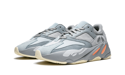 Sneakers Yeezy Boost 700 "Inertia" in grijs en wit, met opvallend design en dikke zool, gedragen door een model.