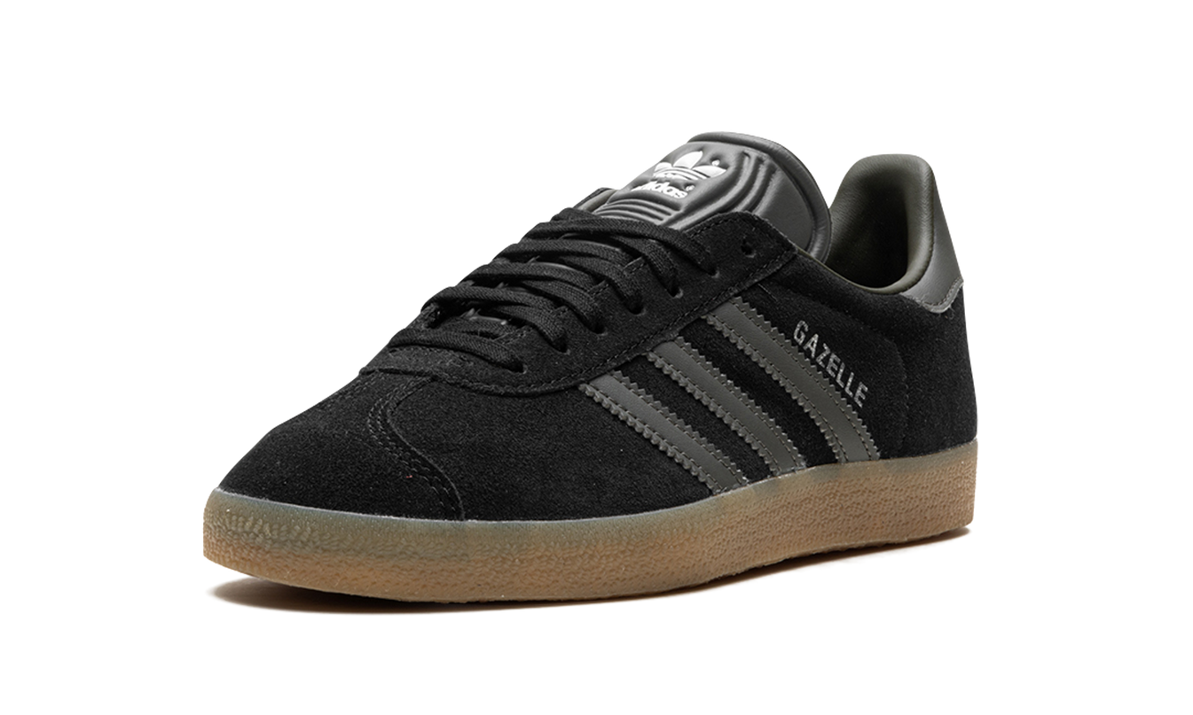 Zwarte Adidas Gazelle schoenen met witte zool en blauwe accenten, zicht van de zijkant, op een witte achtergrond