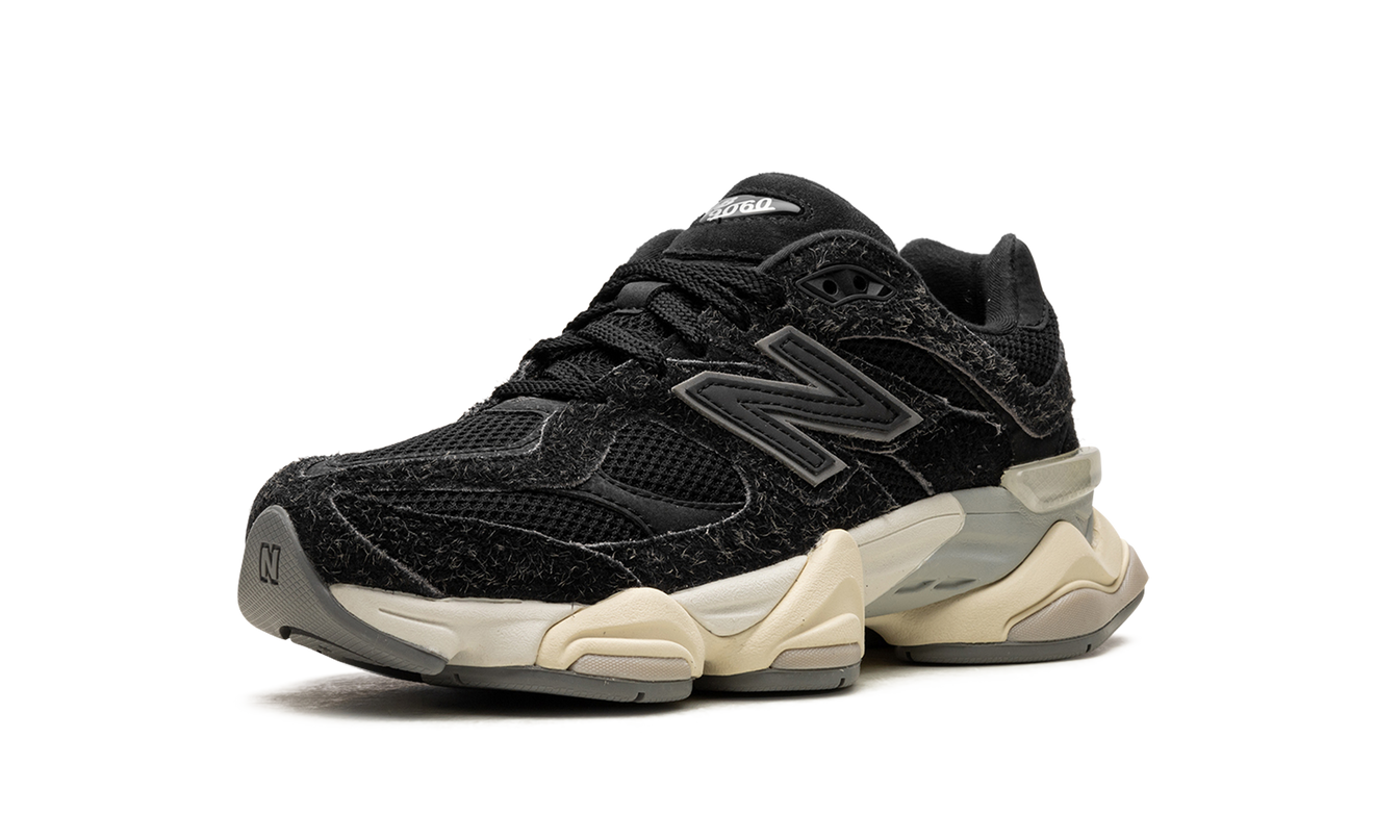Zwarte New Balance 9060 schoenen met suède details, zichtbaar met witzwarte zool en lage veters.