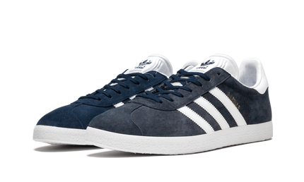 Blauwe Adidas Gazelle schoenen voor dames, met witte zool en leren bovenkant, op een witte achtergrond.