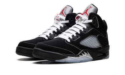Zwarte Air Jordan 5 Retro OG "Black Metallic Reimagined" schoenen met metallic details en witte veters, gedragen door een model.