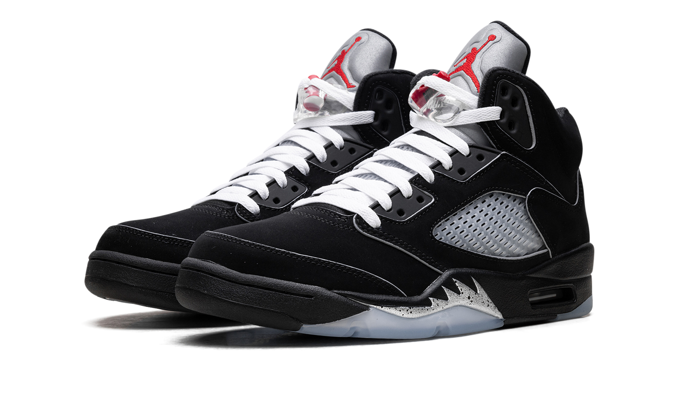 Zwarte Air Jordan 5 Retro OG "Black Metallic Reimagined" schoenen met metallic details en witte veters, gedragen door een model.