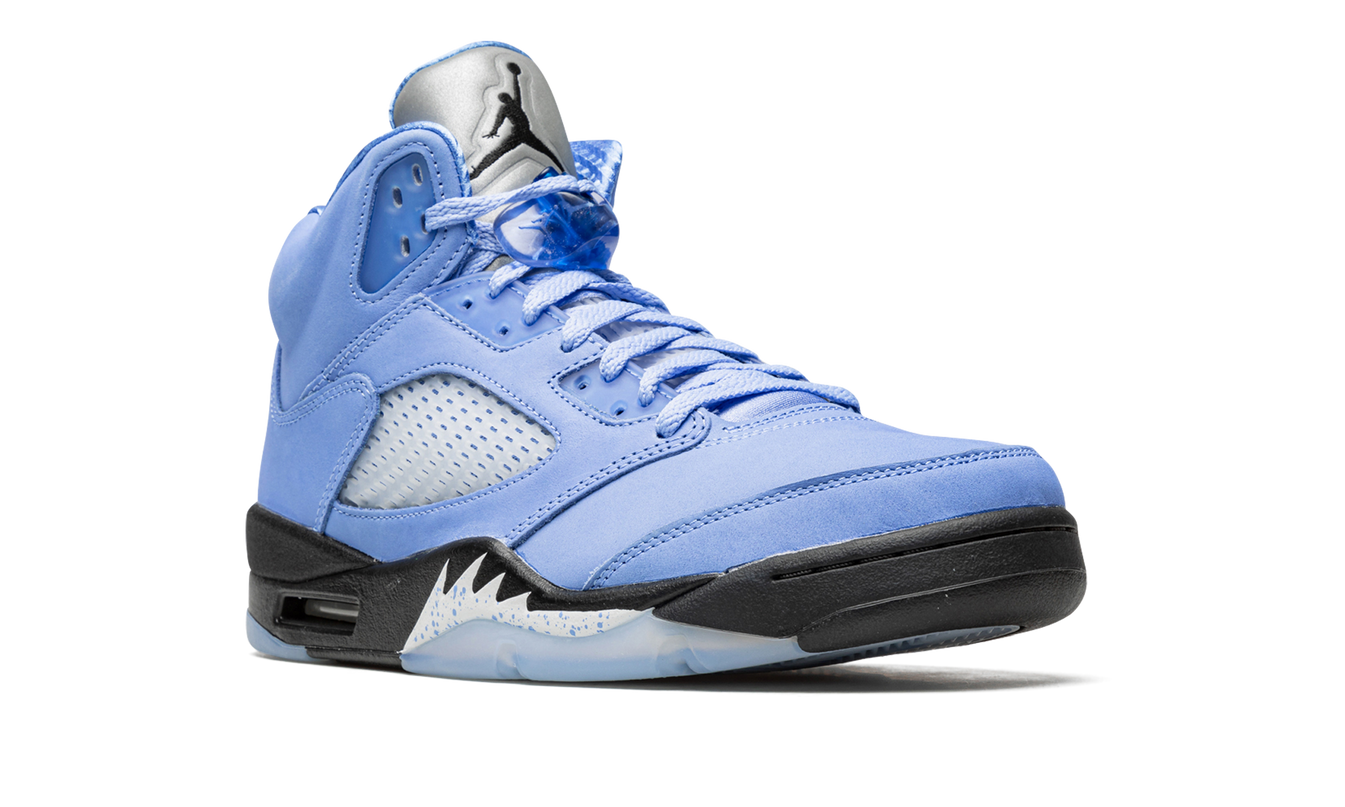 Witte en blauwe Air Jordan 5 Retro SE sneakers met kenmerkende details en merklogo, liggend op een witte achtergrond