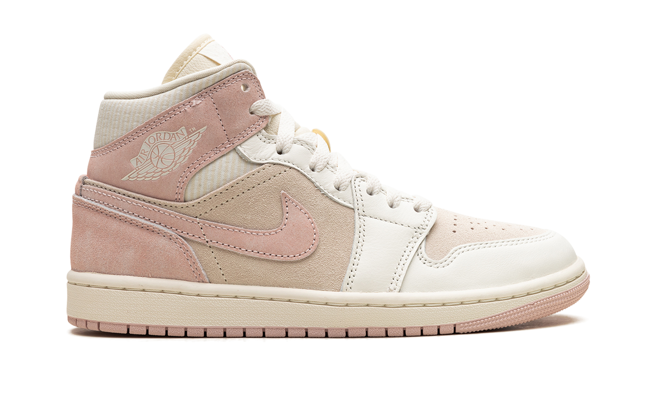 Witte en roze Air Jordan 1 Mid SE WMNS sneakers met kokosmelk- en legendarisch roze details, zichtbaar op de schoen.