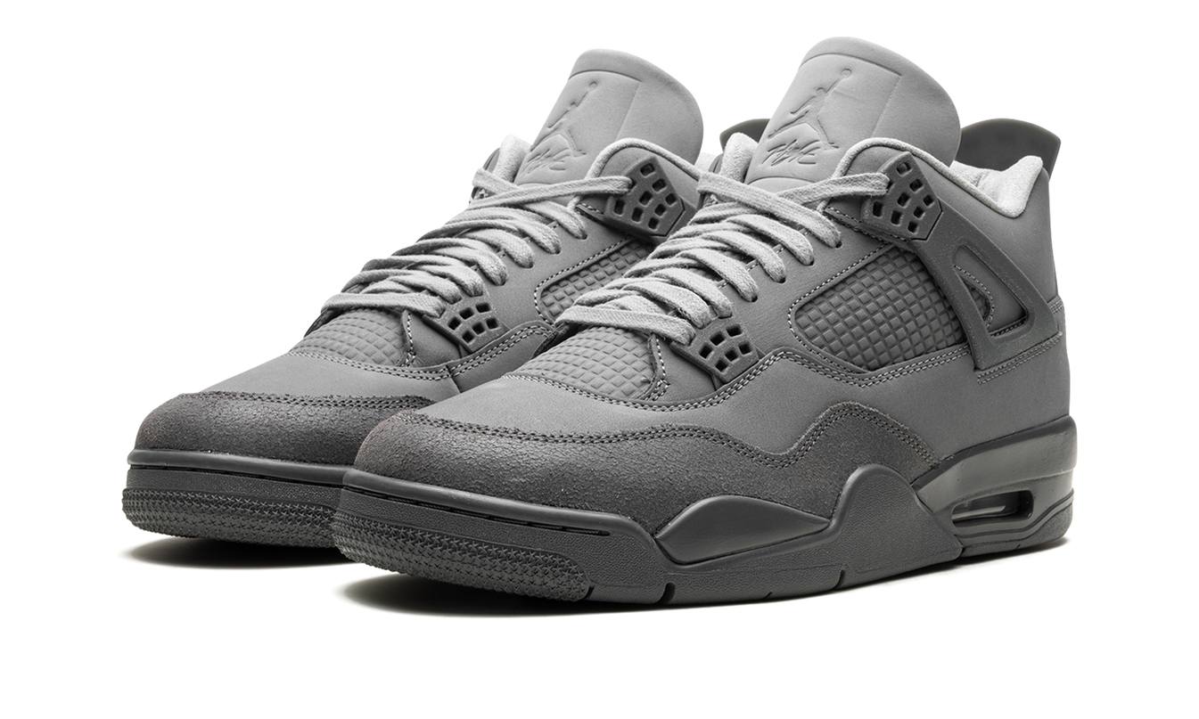 Witte en grijze Air Jordan 4 sneakers "Wet Cement" met witte zool en details, gedragen door een persoon op straat