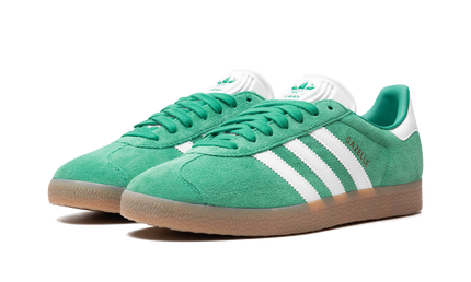 Groene Adidas Gazelle schoenen met gumzool, lage snit en suède bovenkant, zichtbaar op de afbeelding.