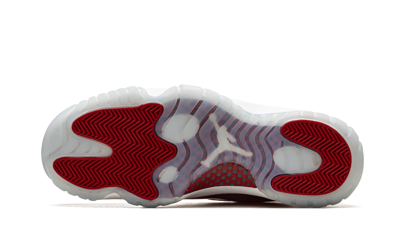 Lichte Air Jordan 11 "Cherry 2022" sneakers met glanzende rode en witte details, zichtbaar in close-up.