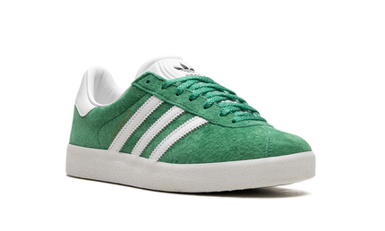 Adidas Gazelle 85 schoenen in Court Green, lage sneakers met groene suède bovenkant en witte zool.
