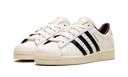 Witte croco sneakers van Wales Bonner, Superstar schoenen in wit met krokodillenpatroon en zwarte details.