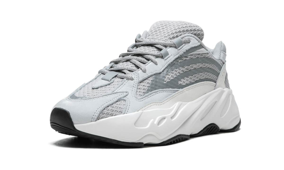 Witte en grijze Yeezy Boost 700 V2 "Static" sneakers met dikke zool en sportief ontwerp, gedragen door een model.