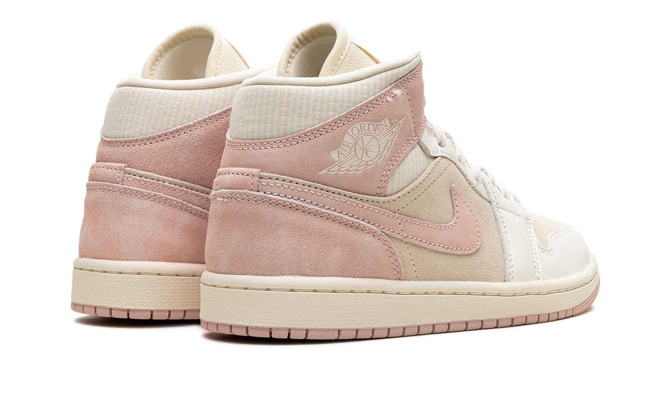 Lichtroze en witte Air Jordan 1 Mid SE damesschoenen met roze en beige details, zichtbaar in close-up.
