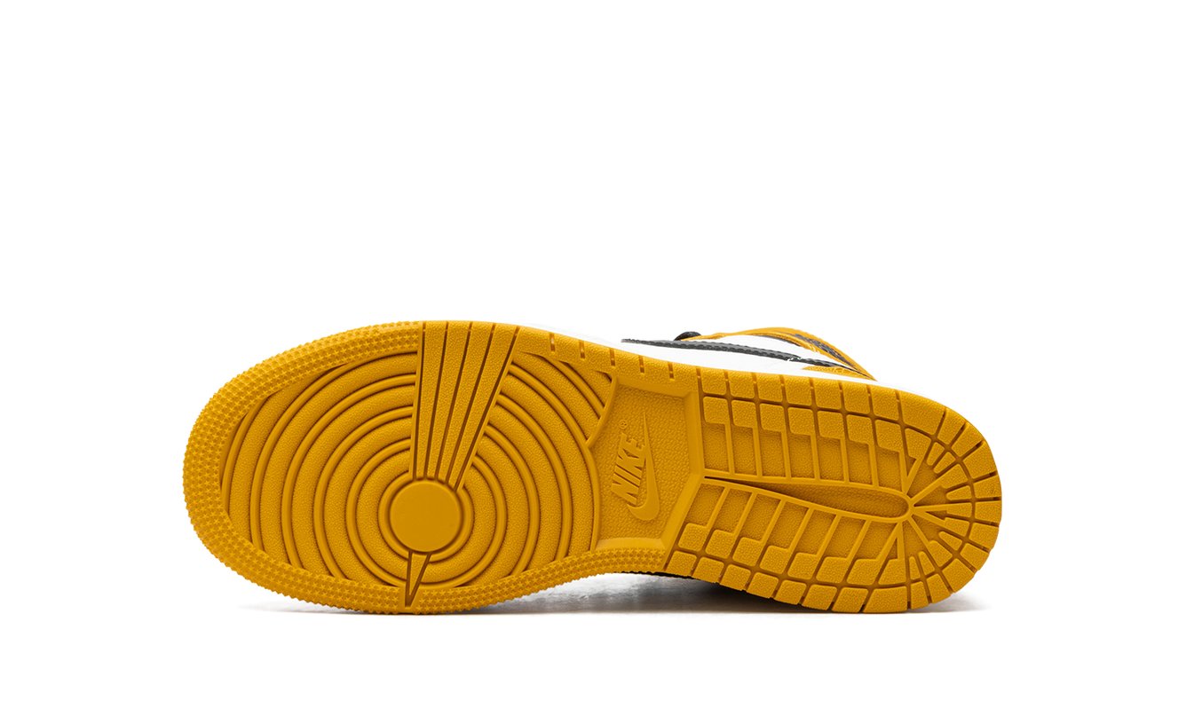 Witte en zwarte Air Jordan 1 Retro High OG GS schoenen met gele oker details, zichtbaar in de afbeelding.