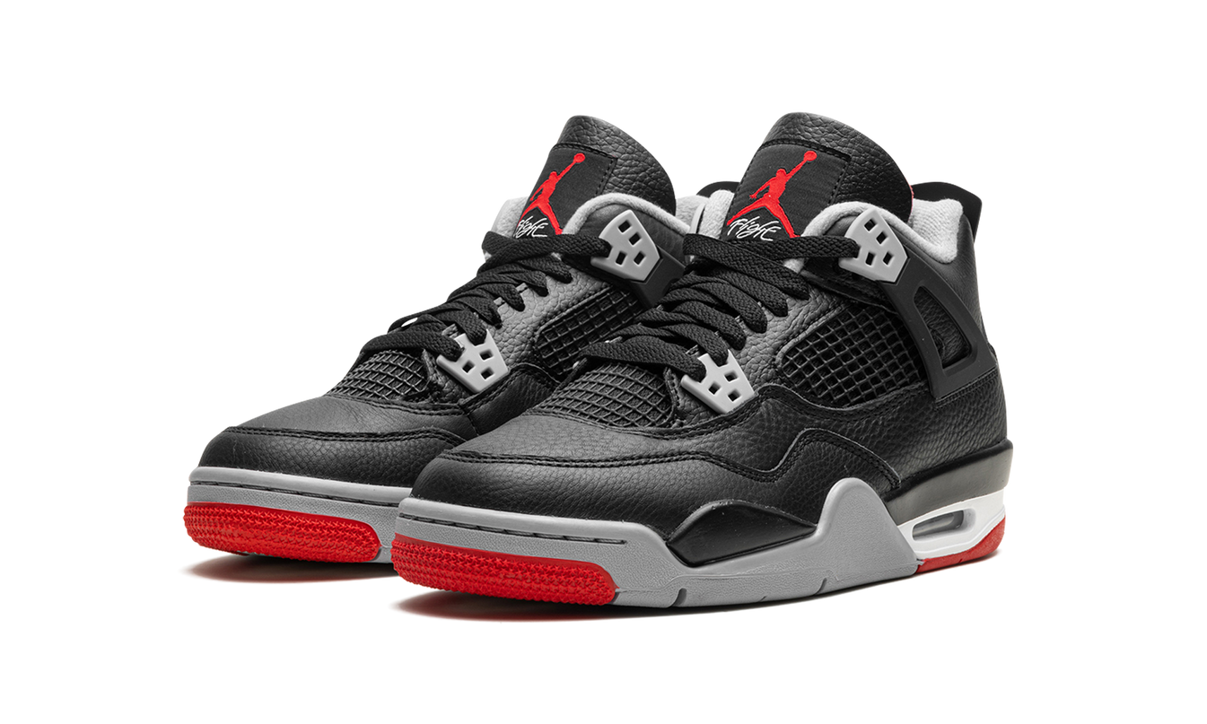 Zwarte Air Jordan 4 GS schoenen "Bred Reimagined" met rode accenten en witte details, zichtbaar in de afbeelding.