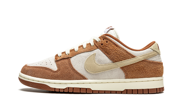 Nike Dunk Low PRM "Medium Curry" schoenen met gele en bruine leren details, zichtbaar op een close-up afbeelding.