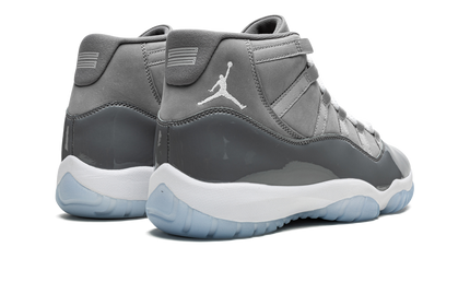 Zwarte Air Jordan 11 Retro "Cool Grey 2021" sneakers met glanzende details en witte zool, gedragen door een persoon.
