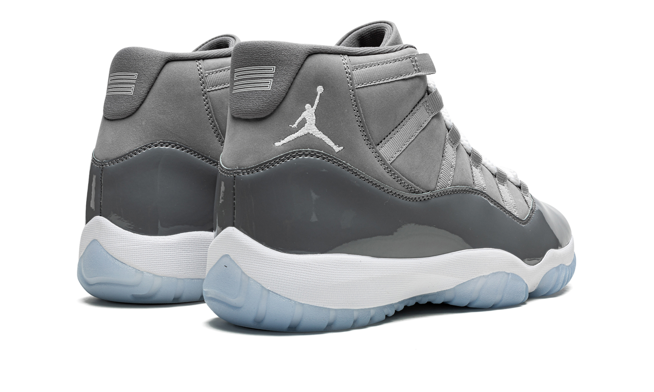 Zwarte Air Jordan 11 Retro "Cool Grey 2021" sneakers met glanzende details en witte zool, gedragen door een persoon.
