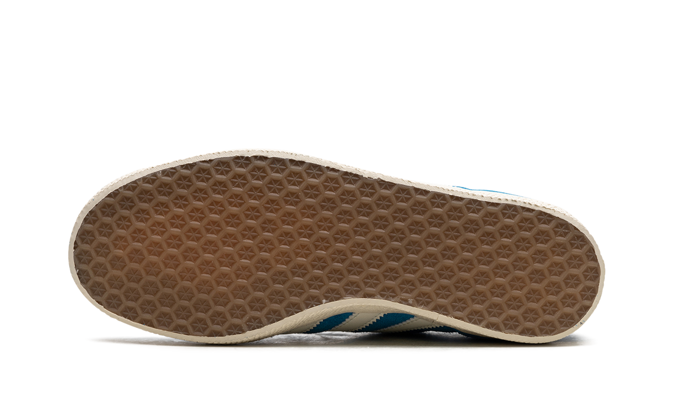 Donkere Adidas Gazelle schoenen in Bold Aqua kleur met witte zool en opvallende details, gedragen door een persoon.