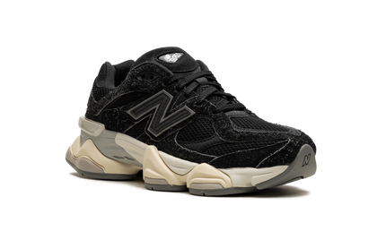 Zwarte New Balance 9060 schoenen met suède details, zichtbaar van de zijkant op een witte achtergrond