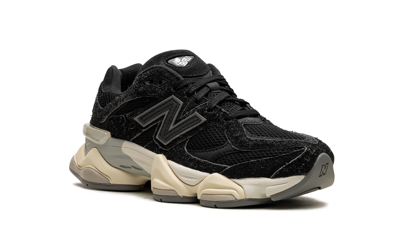 Zwarte New Balance 9060 schoenen met suède details, zichtbaar van de zijkant op een witte achtergrond