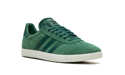 Donkergroene Adidas Gazelle sneakers voor dames met witte accenten en leren details, op een witte achtergrond.