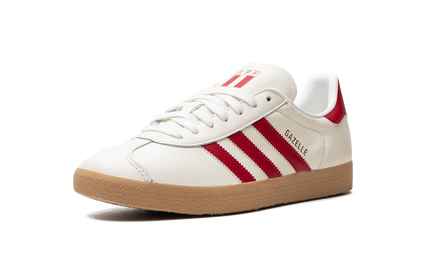 Adidas Gazelle "Peru" schoenen in beige en wit met suède details en witte veters, gelegen op een houten vloer.