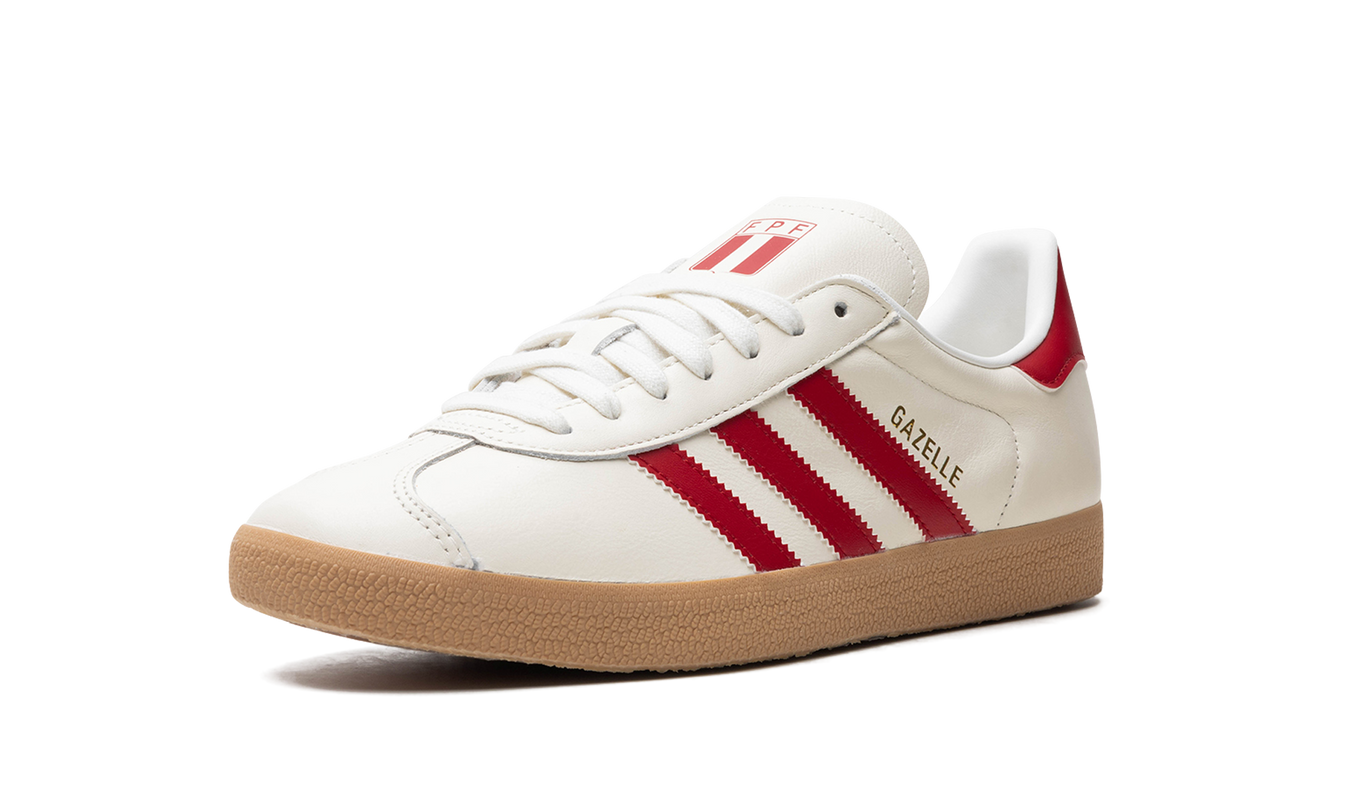 Adidas Gazelle "Peru" schoenen in beige en wit met suède details en witte veters, gelegen op een houten vloer.