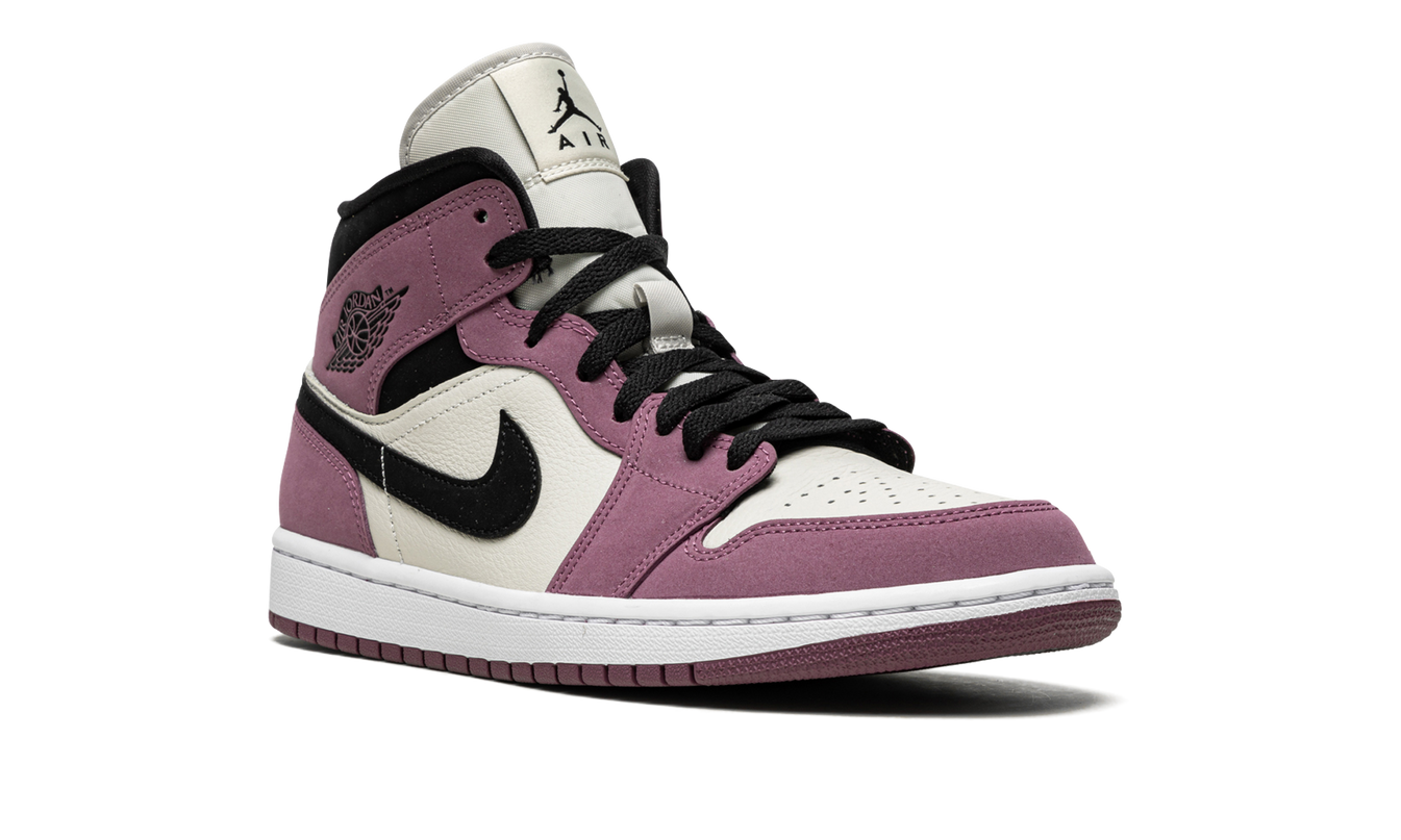 Witte en roze Air Jordan 1 MID SE WMNS sneakers met roze details en zwarte accenten, zichtbaar van de zijkant.