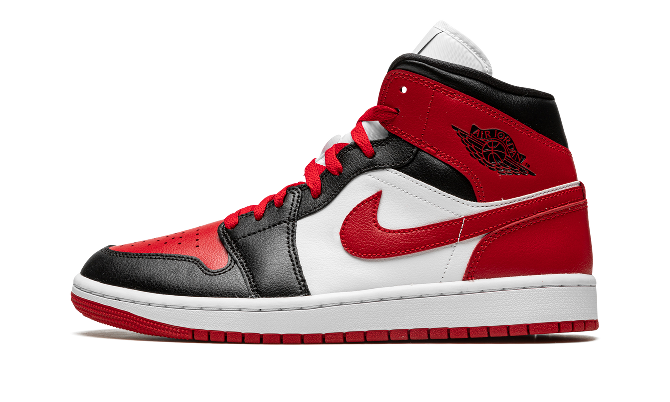Witte en rode Air Jordan 1 MID WMNS schoenen met zwarte details, zichtbaar in close-up met focus op de sneakers.