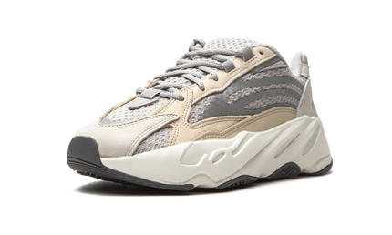 Witte Yeezy Boost 700 V2 schoenen met cream-kleurige details en dikke zool, gedragen door een model in een lichte setting.