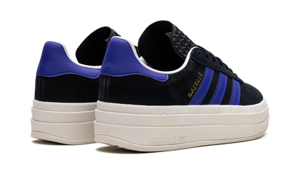 Zwarte Adidas Gazelle BOLD WMNS sneakers met blauwe details, zichtbaar op een witte achtergrond.